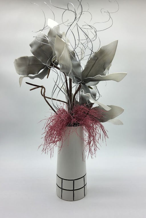 White/Black vase filled with grey foam flowers, pink grass, silver branches