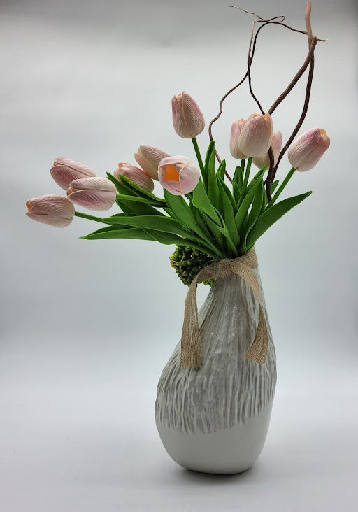 White vase filled with pink tulips, green cactus and brown twigs