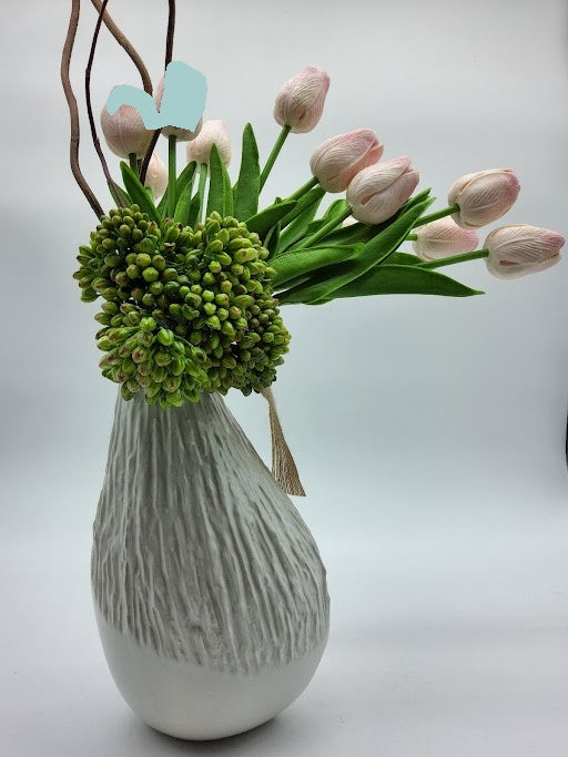 White vase filled with pink tulips, green cactus and brown twigs